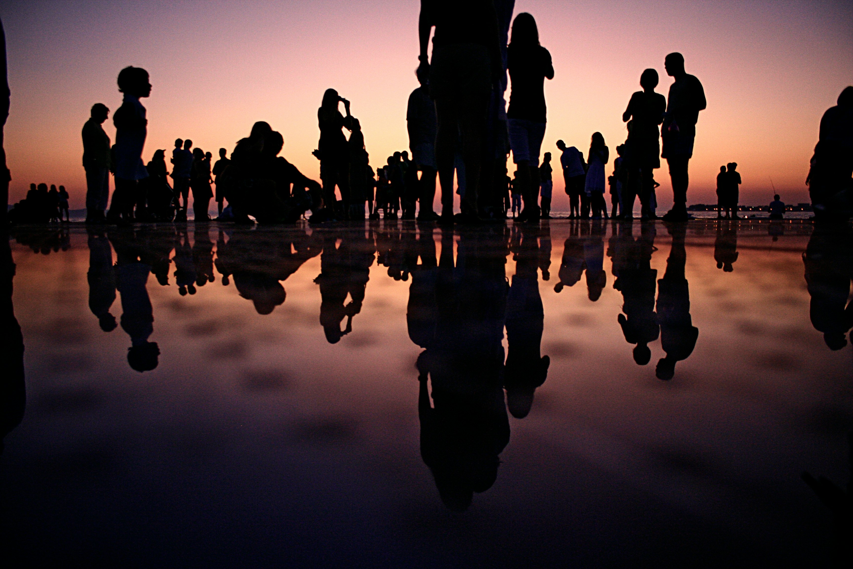 silhouette of people standing on mirror during golden hour